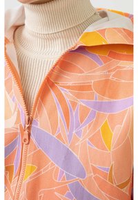 Hoodiejakke med lynlås i nuancer af orange med lilla og gule abstrakte mønstre. Fremstillet af glat stof med en ribbet tekstur og en højhalset trøje nedenunder.