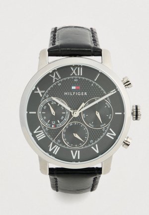 Reloj de pulsera Tommy Hilfiger para hombre con correa de cuero negro, caja plateada, esfera negra, números romanos y tres subesferas para 24 horas, fecha y día.