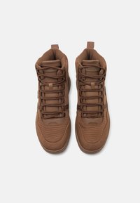 Brązowe sneakersy typu high-top wykonane z teksturowanej tkaniny. Charakteryzują się wyściełanym kołnierzem, sznurowanym przodem oraz logo na języku. Wytrzymała gumowa podeszwa.