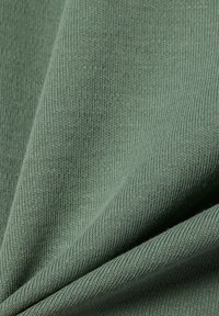 Light green knit fabric with a smooth texture, featuring tightly woven fibers and a slightly ribbed surface. No distinct patterns or accents visible.