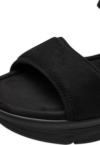 Fekete velúr szandál széles pánttal, párnázott talprésszel és texturált gumitalppal a jó tapadás érdekében. Egyszerű design, látható fémalkatrészek nélkül.