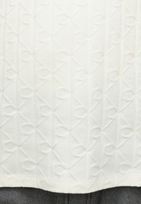 Weißer strukturierter Stoff mit einem geometrischen Muster und erhabenen kreisförmigen Akzenten, gestaltet in rechteckiger Form. Der Rand ist mit einem glatten Saum versehen.