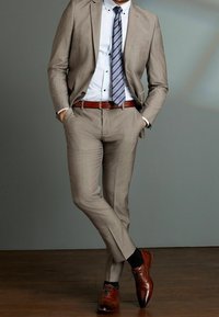 Traje marrón claro a medida con una textura sutil, acompañado de una camisa azul claro a rayas y una corbata azul oscura a rayas. Zapatos de cuero marrón.