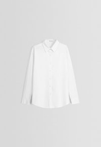 Camicia bianca a maniche lunghe realizzata in tessuto morbido, con colletto classico, chiusura a bottoni e orlo arrotondato. Dettagli di cucitura discreti sui polsini.