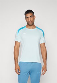 Világoskék, rövid ujjú sportpóló fehér és aquakék díszítéssel. A mellkason található a Nike logó, és kerek nyakú. Sima textúrájú.