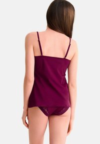 Bordeaux camisole met verstelbare spaghettibandjes en een gladde stof, gecombineerd met bijpassende onderbroek met transparante afwerking, gezien van achteren.