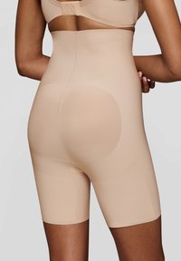 Bermuda beige senza cuciture con vita alta, texture liscia e aree rinforzate per il supporto. Ideali per una silhouette snella.