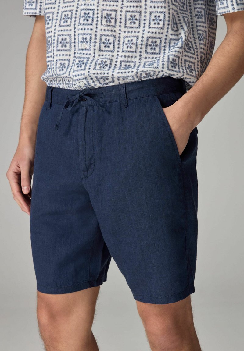 Mørkeblå shorts lavet af letvægtsstof, med snor i taljen, sidelommer og en afslappet pasform. Glat tekstur med minimal syning.
