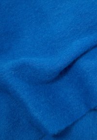 Blødt blåt filtstof med en struktureret overflade, der viser varierende nuancer af blåt, folder og et fluffy udseende.