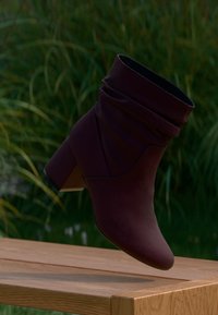Burgundy ankle boot made of soft textile material, featuring a slouchy design, pointed toe, and a medium block heel.