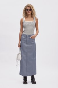 Csíkos ujjatlan felső, denim maxi szoknya elülső varrással, ezüst csattal ellátott táska, fekete bokacsizma, göndör haj és napszemüveg.