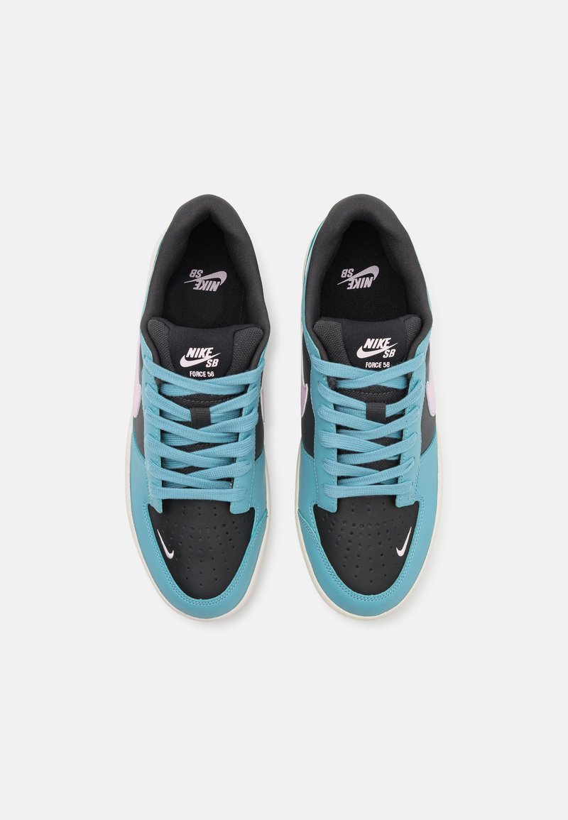 Zapatillas Nike SB con parte superior de cuero en turquesa y negro, puntera perforada, acentos en rosa y cordones negros. Suela blanca con logo.