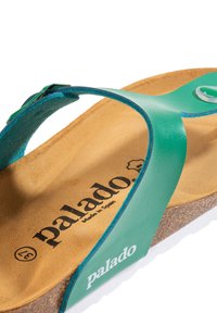 Grön syntetisk tanga sandal med en korkfotbädd. Har en slät yta, en vit sula och "palado"-logotypen på fotbädden.