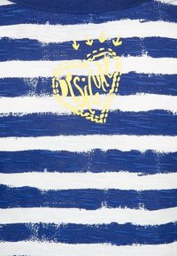 Niebieska i biała koszulka w paski o teksturowanym wyglądzie, z żółtym graficznym sercem z napisem "BSIC" na środku, z dodatkowymi akcentami w kształcie strzałek.