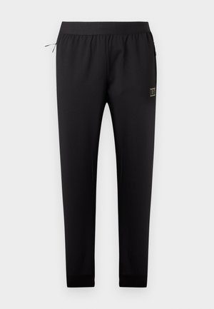 Μαύρο φαρδύ παντελόνι φόρμας με ελαστική μέση, πλαϊνή τσέπη με φερμουάρ και μικρό ορθογώνιο λογότυπο στο δεξί μηρό.