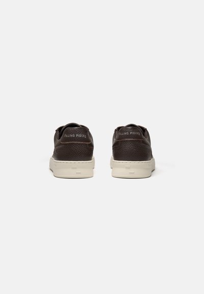 Een paar donkerbruine leren sneakers met witte zolen, gezien van achteren, met "Filling Pieces" branding op het hielstuk.