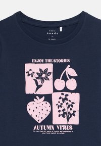 Marineblaue Baumwoll-T-Shirt mit rundem Ausschnitt, das vier rosa grafische Quadrate mit Früchten und Blumen zeigt, sowie den Text "ENJOY THE STORIES" und "AUTUMN VIBES."