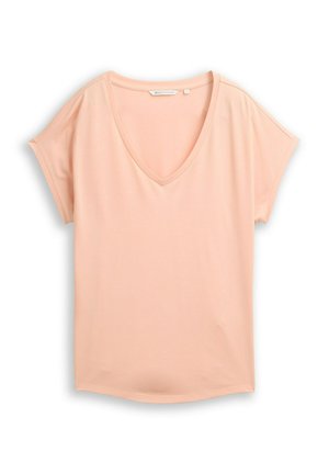 T-shirt à manches courtes couleur pêche clair avec col en V, coupe ample et détail subtil de couture sur les manches, posé à plat sur un fond blanc.