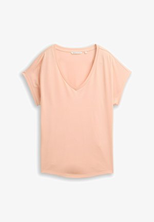 Krótki T-shirt w jasnym brzoskwiniowym kolorze, z dekoltem w serek, luźnym krojem i subtelnym przeszyciem na rękawach, położony na białym tle.