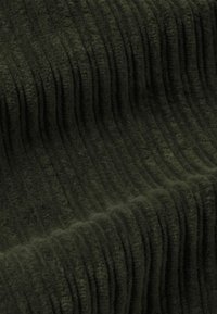 Mörkgrönt manchestertyg med vertikal räfflad struktur, mjuk yta och en tjock, plyschliknande känsla, som visar jämna linjer och djup.