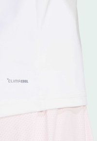 Valge ClimaCool sportlik särk, millel on sile tekstuur ja lühike äär, koos kerge roosa võrkkihiga all. 