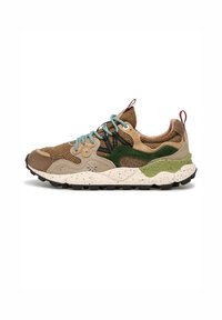 Zapatilla de deporte de caña baja con paneles de ante y tela en marrón, beige y verde, cordones azules, suela texturizada y tiradores rojos en la lengüeta y el talón.
