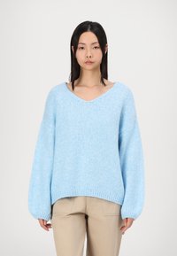 Lichtblauwe oversized trui met een V-hals, lange mouwen en geribde manchetten. Gemaakt van een gebreide stof met textuur, met een relaxte pasvorm.