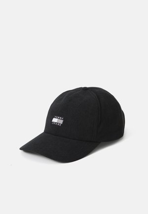 Sort corduroy baseball cap med et frontpatch med teksten "TOMMY JEANS", buet skygge og ventilationshuller på toppen.