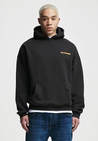 Black hoodie made of soft fabric, featuring a front pocket and cuffed sleeves. Embroidered logo in orange on the chest. Casual fit.