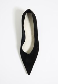 Zapato de salón negro de ante con punta afilada y escote en forma de V en la parte delantera. La plantilla es de color crema, complementando la parte superior texturizada.