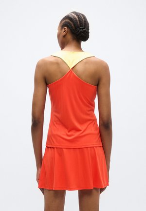 Rode atletische jurk met een uitlopende rok, voorzien van gele accenten op de schouder en een verticale krijtstreepstructuur. Het ontwerp aan de achterkant heeft een racerback.