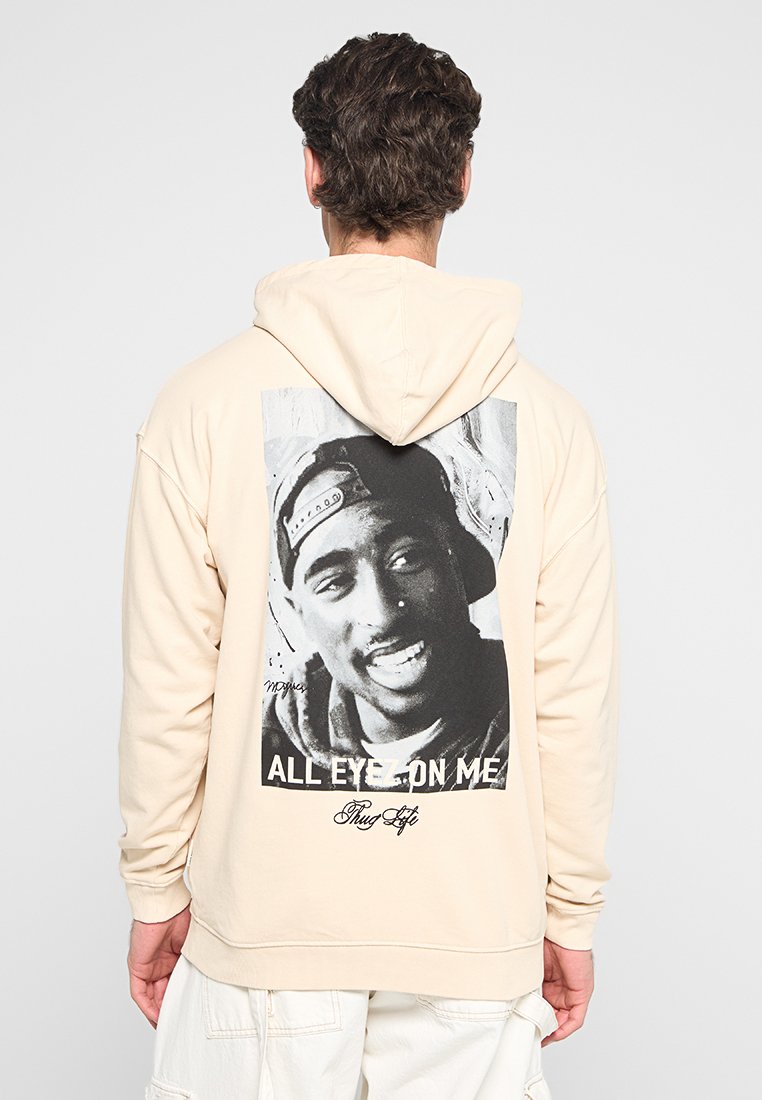 Felpa color crema con un graficore sul retro che presenta un ritratto in bianco e nero, con il testo "ALL EYEZ ON ME" e "Thug Life" in basso.