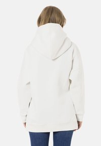 White hooded sweatshirt with a loose fit, dropped shoulders, and ribbed cuffs. Smooth texture, featuring a large, spacious hood.