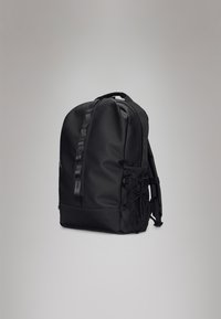 Mochila preta com um acabamento mate e suave. Possui alças ajustáveis, um bolso lateral em malha e um zíper resistente. Design simples e funcional.
