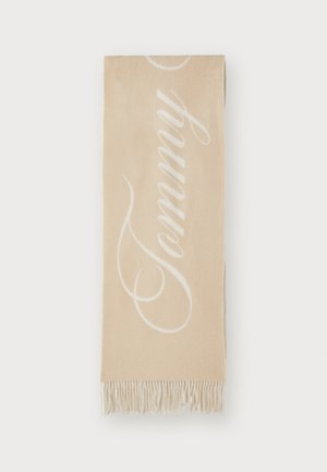 Μπεζ κασκόλ με μεγάλη λευκή γραφή "Tommy", με φούντες στα άκρα και μαλακό, υφασμένο ύφασμα. Απλός σχεδιασμός με αντίθετα χρώματα.