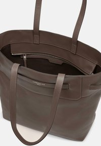 Brun läder toteväska med två medellånga handtag, som har en dragkedjeficka inuti och en slät yta med små sömnadsdetaljer.