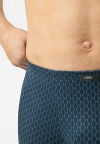 Boxers pour hommes à motifs bleus avec une taille lisse, comprenant un design de vague subtil en bleu clair. Étiquette visible sur la taille.