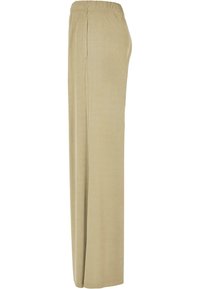 Pantalon beige à jambes larges avec taille élastique, coupe droite et détail de couture latérale, présenté de profil sur un fond uni.