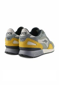 Graue, gelbe und schwarze Sneaker aus Wildleder und Netzmaterial. Auffällige Merkmale sind das Branding an der Ferse und die strukturierte Gummisohle.