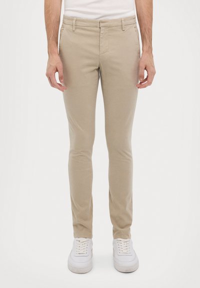 Chinos beige en mélange de coton, coupe slim, devant plat, poches latérales et texture lisse. Associés à des baskets blanches.