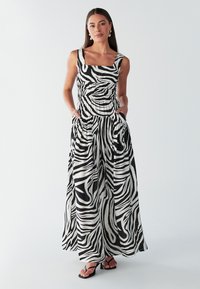 Vestito lungo a righe bianche e nere con scollo quadrato, vita arricciata e tasche. Tessuto leggero con una silhouette fluida.