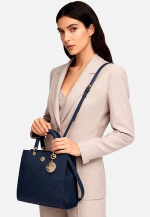 Borsa blu navy in pelle liscia, con design trapuntato diagonale, dettagli in oro e due opzioni di trasporto: manici corti e tracolla lunga.