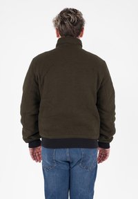 Giacca in pile verde oliva con colletto alto, polsini e orlo a costine. Presenta un design corto, una morbida texture e senza chiusure visibili.