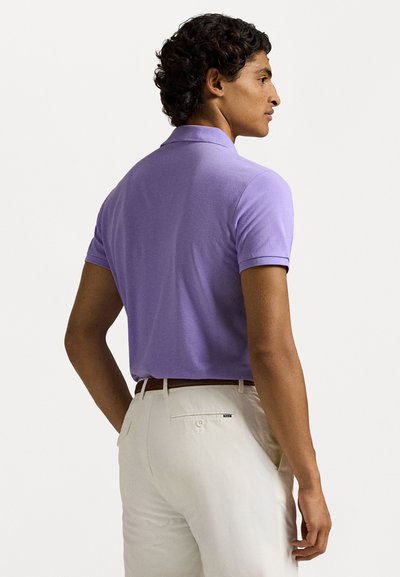 Πόλο μπλούζα κοντό μανίκι σε ανοιχτό λεβάντα με υφή, διαθέτοντας κλασικό γιακά. Συνδυάζεται με μπεζ παντελόνια και λεπτομέρεια πίσω τσέπης.