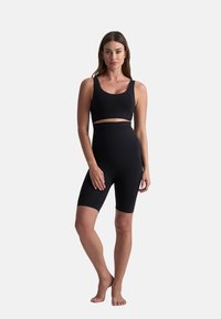Zwart activewear-set met een strakke bralette-top en high-waisted shorts, gemaakt van soepel, elastisch materiaal met naadloze randen.