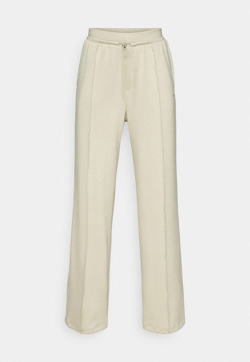 Pantaloni sportivi a gamba larga color beige chiaro in tessuto morbido, con vita regolabile tramite lacci e tasche laterali; presenta dettagli di cucitura verticale lungo i lati.