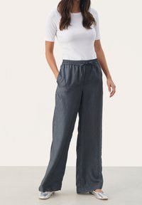 Spodnie o szerokich nogawkach z miękkiego, teksturowanego ciemnoszarego materiału z elastycznym pasem i regulowanym sznurkiem, zestawione z dopasowanym białym topem.
