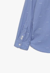 Blauw gestreepend overhemd met witte tekstpatronen, manchetten met knoopdetail en een gladde stoftextuur. Het ontwerp bevat een taps toelopende mouw en kraag.