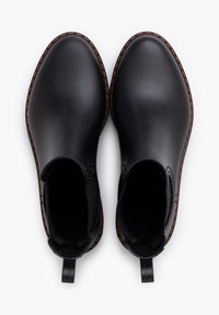 Bottes noires en caoutchouc jusqu'à la cheville avec des panneaux latéraux élastiques, des coutures renforcées en marron et des languettes au niveau du talon pour un enfilage facile. Semelle plate.