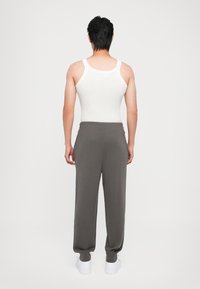 Grå sweatsbukser med løs passform og elastiske mansjetter, sammen med en hvit tanktopp. Stoffet ser mykt ut med et avslappet design.